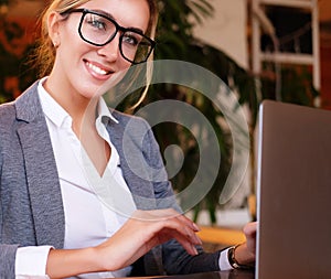 Businesswoman Working On Laptop In Coffee Shop. Young business woman uses laptop in cafe.