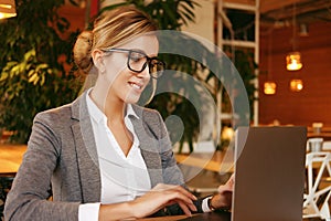 Businesswoman Working On Laptop In Coffee Shop. Young business woman uses laptop in cafe.