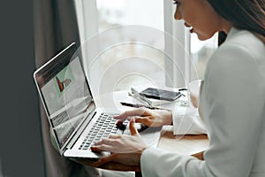 Businesswoman working on laptop computer managing her business via office.