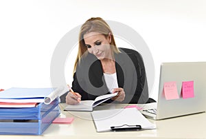 Businesswoman working at laptop computer office desk taking notes writing on notebook