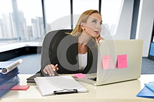 Businesswoman working at laptop computer sitting on the desk absent minded