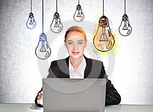 Businesswoman working with laptop inspired, light bulb sketches on grey wall