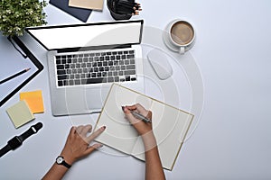 Business woman working with laptop and making notes on notebook.