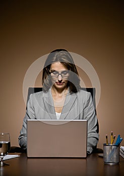 Businesswoman working late and typing on laptop