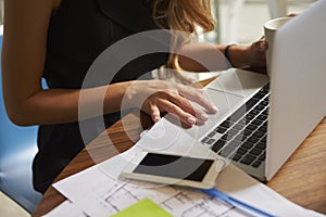 Businesswoman working in office using laptop, mid section