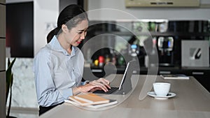 Businesswoman working online with computer  tablet at home kitchen counter.