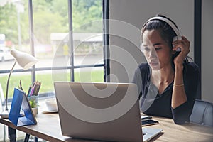 Businesswoman working online at the home office via laptop. Asian young entrepreneurs watching webinars and talking during meeting