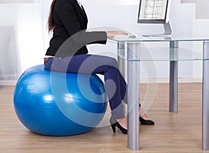 Businesswoman working while sitting on pilates ball