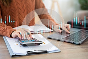 Businesswoman working with tablet and using a calculator to calculate the numbers of static in office. Finance accounting concept