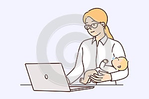 Businesswoman works with baby in arms using laptop to complete freelance orders online