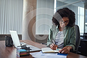 Businesswoman writing in an agenda on a desk at office