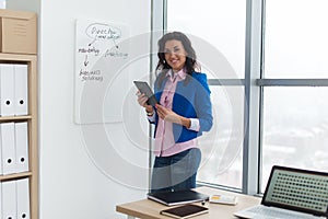 Businesswoman writing day plan on white board, modern office. Side view of caucasian female employee planning schedule