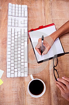 Businesswoman writing on diary on desk