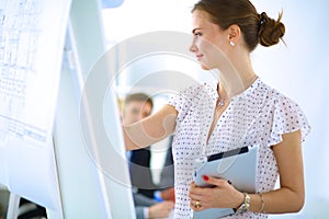 Businesswoman writing on flipchart while giving presentation to colleagues in office