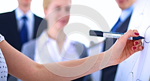 Businesswoman writing on flipchart while giving presentation to colleagues in office