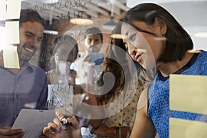 Businesswoman Writing Ideas On Glass Screen During Meeting