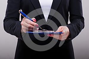 Businesswoman writing in ink on the clipboard