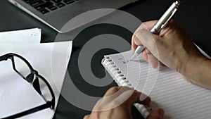 Businesswoman writing KPIs with pen on notepad.