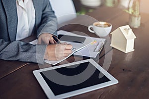 Businesswoman writing on paper real estate documents