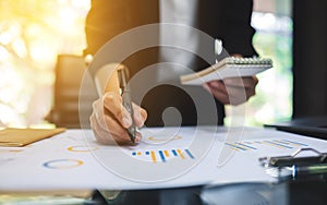 A businesswoman writing and working on business financial data on the table