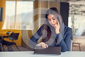 Businesswoman yawning while working with a laptop computer in the office, a woman in casual office lifestyle concept.