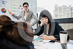 Businesswoman yelling at colleagues who doze off