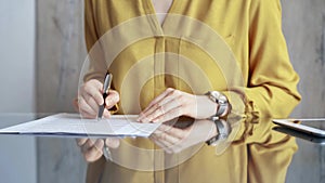 Businesswoman in yellow blues analyzing document at desk. Close-up of a professional auditor or lawyer reviewing a