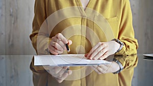 Businesswoman in yellow blues analyzing document at desk. Close-up of a professional auditor or lawyer reviewing a