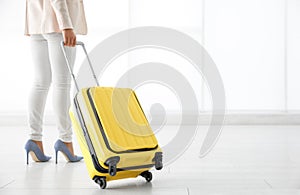 Businesswoman with yellow travel suitcase in airport. Space for text