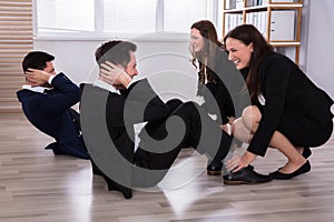 Businesswomen Assisting Male Colleagues While Doing Exercise