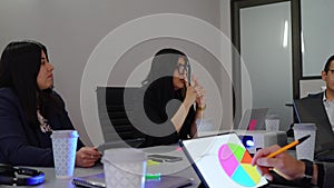 businesswomen conducting a business meeting in an office, woman CEO leader speaking with work team analyzing graphics on a tablet