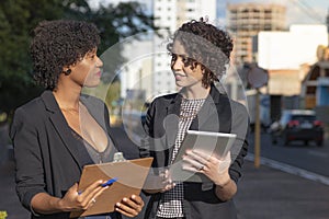 Businesswomen conducting conversation using spreadsheet and tablet