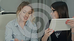 Businesswomen with digital tablet exchanging ideas in modern office