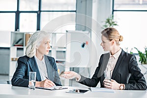 Businesswomen gesturing and discussing business project on meeting in office