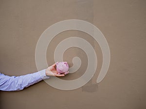 Businesswomen hand holding pink piggy bank on brown cement wall background, Saving money for future plan and retirement fund