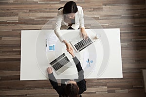 Businesswomen handshaking above office desk making successful de