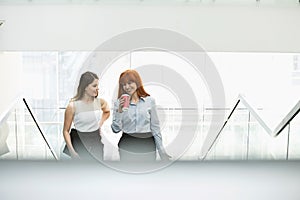 Businesswomen having coffee while moving up steps in office