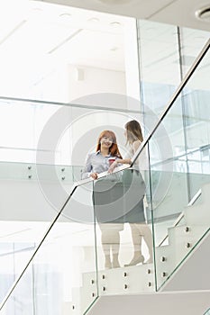 Businesswomen having coffee while standing on steps in office