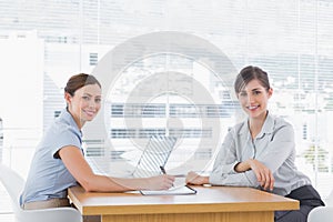 Businesswomen having a meeting at desk and smiling at camera