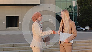 Businesswomen Indian girl in hijab and young European woman in formal clothes finalizing negotiations say goodbye