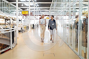 Businesswomen interacting with each other while walking in a modern office