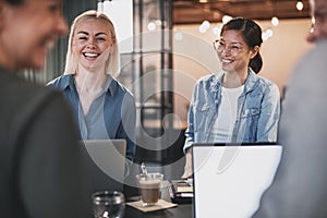Businesswomen laughing with colleagues during an office meeting