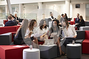 Businesswomen Meeting In Busy Lobby Of Modern Office
