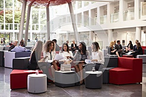 Businesswomen Meeting In Busy Lobby Of Modern Office