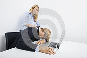 Businesswomen with overworked coworker at desk in office