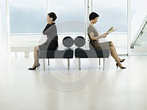 Businesswomen With Phone And Newspaper In Opposite Directions At