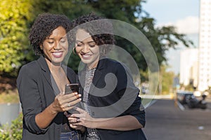 Businesswomen sending message by cellphone