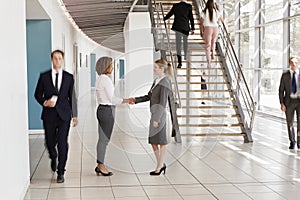 Businesswomen shaking hands in a busy modern lobby