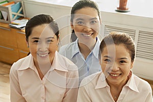 Businesswomen smiling and looking up at camera, in the office