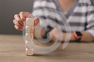 Businesswomen stack blank wooden cubes on the table with copy space, empty wooden cubes for input wording, and an infographic icon